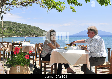 Ein Paar, das eine Meeresfrüchte-Mahlzeit im Maurias Restaurant Gikes neben dem Hafen von Epidavros, Peloponnes, Griechenland, genießt Stockfoto