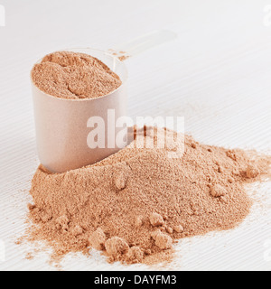 Kugel Schokolade Molke-Protein-Pulver zu isolieren oder Gewicht Verlust Pulver Verschütten aus einen Messbecher auf weißen Holzbrett Stockfoto