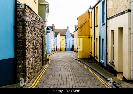 Attraktive Pastelle farbigen Reihenhäusern aufhellen eine Straße mit Kopfsteinpflaster Glitzern nach einem letzten Regen in Tenby Stockfoto