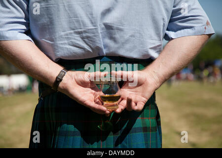 Man Glas Scotch Whisky in Tomintoul, Schottland, Großbritannien. 20. Juli 2013. Die jährlichen Spiele und Zusammenkünfte der Tomintoul Highland finden am 3. Samstag im Juli auf dem Ausstellungsgelände im Dorf statt. Dieses sportliche, historische und traditionelle schottische Ereignis in den vergangenen Jahren wurde von schlechtem Wetter heimgesucht und mehrmals abgesagt. Stockfoto