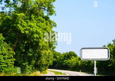 Leere Schild an einer Straße mit grünen Bäumen Stockfoto