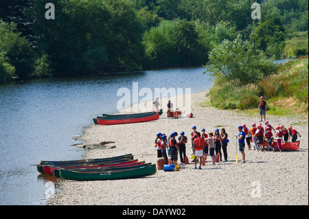 Gruppen der Kinder erhalten Unterricht in offenen Kanus am Ufer neben Fluss Wye bei Glasbury Powys Wales UK paddeln Stockfoto