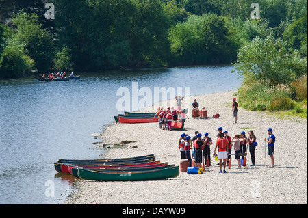 Gruppen der Kinder erhalten Unterricht in offenen Kanus am Ufer neben Fluss Wye bei Glasbury Powys Wales UK paddeln Stockfoto