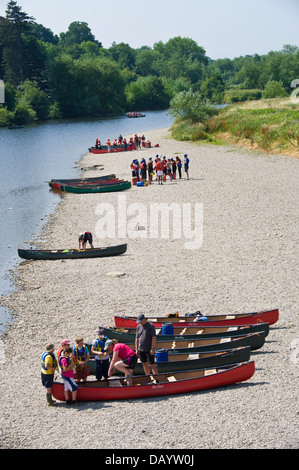 Gruppen der Kinder erhalten Unterricht in offenen Kanus am Ufer neben Fluss Wye bei Glasbury Powys Wales UK paddeln Stockfoto