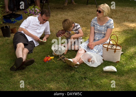 Familie entspannend auf Rasen am Worldham Dorffest, Hampshire, UK. Sonntag, 14. Juli 2013. Stockfoto