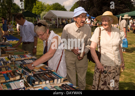 Buch-Stall & älteres Ehepaar Spazierengehen Worldham Dorffest, Hampshire, UK. Sonntag, 14. Juli 2013. Stockfoto