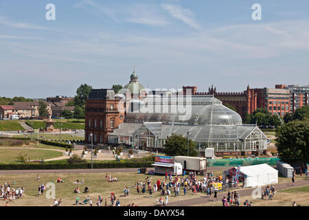 Glasgow, Schottland, 21. Juli 2013. Einige Besucher der Glasgow Show 2013 auf Glasgow Green. Im Hintergrund sind die Menschen Palast und der Doulton Brunnen der Templeton-Business-Center (ehemals Templeton Teppich Fabrik). Stockfoto