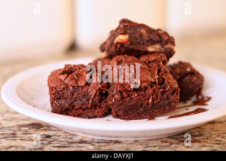 Eine Platte von zu Hause hergestellt Schokoladen-Brownies mit Pekannüssen, einige ohne, bedeckt mit einer Schokolade Nieselregen. Stockfoto