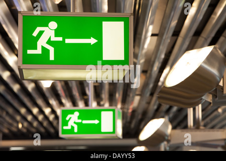 Grünen Ausgang Leuchttransparente an der Decke befestigt. Die Zeichen verfügen über menschliche Figuren, die auf eine Ausgangstür ausgeführt. Stockfoto