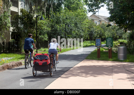 Paar Fahrrad ziehen Anhänger Kinderwagen Schienen Trails Depot Radweg neben dem Campus der University of Florida. Stockfoto