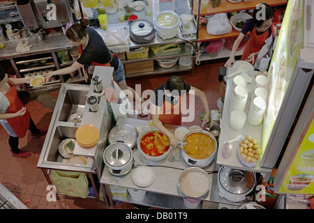 Leute, die in der Küche in einem Hawker Center in Singapur arbeiten. Stockfoto