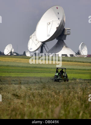 Ein Bauer wird Heu mit einem Traktor vor Telekoms Erdefunkstelle Antennen in der Nähe von Raisting auf See "Ammersee", Deutschland, 8. Juni 2007. Temperaturen um die 30 Grad werden in den nächsten Tagen herrschen. Foto: Matthias Schrader Stockfoto