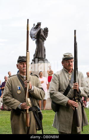 Konföderierten Civil War Reenactor stehen durch das Denkmal für die Konföderation während einer Zeremonie, die Enthüllung eines Denkmals zu Ehren der 54. Massachusetts Volunteer Infantry auf dem 150. Jahrestag des Angriffs auf Batterie Wagner 21. Juli 2013 in Charleston, SC. Die Schlacht im Film 'Ruhm' nahm in den Gedenkzustand versetzt in Charleston und war die erste große Schlacht von einer alle schwarzen Regiment. Stockfoto