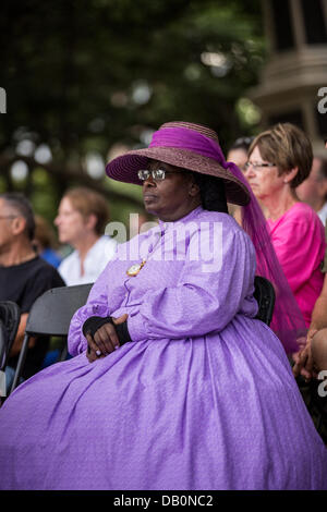 Eine Frau, die im Bürgerkrieg Kostüm gekleidet hört während einer Zeremonie, die Enthüllung eines Denkmals zu Ehren der 54. auf dem 150. Jahrestag des Angriffs auf Batterie Wagner 21. Juli 2013 in Charleston, SC. Die Schlacht im Film 'Ruhm' nahm in den Gedenkzustand versetzt in Charleston und war die erste große Schlacht von einer alle schwarzen Regiment. Stockfoto