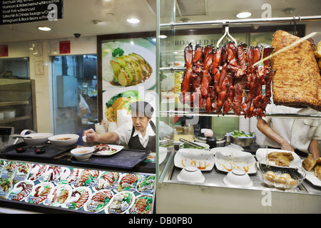 Essensstand serviert traditionelle asiatische Gerichte in einem überdachten Hawker-Center. Singapur. Stockfoto