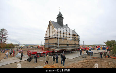 Die Menschen sehen, wie die Emmaus-Kirche mit einem speziellen Fahrzeug in Heuersdorf, Deutschland, 23. Oktober 2007 verschoben wird. Aufgrund der nahenden Kohle-Streifen 750 Tonnen Bergbau ist schwere Kirche von Heuersdorf in benachbarten Borna transportiert. Auf dem Weg zu seiner neuen Ziel zwei Zug müssen Kreuzungen und drei Brücken bestanden werden, bevor die Dienste wieder auf die Kirche an Ostern 2008 gehalten werden können. Bei pre Stockfoto