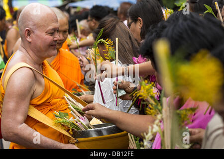 Phra Phutthabat, Saraburi, Thailand. 22. Juli 2013. Ein Mönch erhält Blumen von der Masse während der Tak Bat Dok Mai am Wat Phra Phutthabat in Saraburi Provinz von Thailand, Montag, den 22. Juli. Wat Phra Phutthabat ist berühmt für die Art und Weise, die es markiert den Beginn der Vassa, der drei-Monats-Klausurtagung von Theravada Mönche und Nonnen beobachtet. Der Tempel ist in Thailand hoch verehrt, weil es einen Schritt des Buddha beherbergt. Am ersten Tag der Vassa (oder buddhistischen Fastenzeit) Menschen kommen Sie zum Tempel '' machen Verdienst '' und die Mönche dort mit Tanz Dame Ingwer Blumen, die blühen nur in das, was wir präsentieren Stockfoto