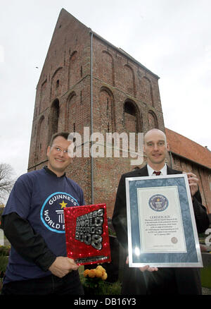 OLAF Kuchenbecker (L) von der Guiness-Buch der Rekorde-Redaktion und Pastor Frank Wessels Pose vor der schiefen Kirche Turm als sie vorhanden das Guiness-Buch der Rekorde-Zertifikat in der ostfriesischen Stadt von Suurhusen, Deutschland, 8. November 2007. Das Zertifikat zeichnet offiziell den Turm in Suurhusen als weltweit die meisten schiefen Turm, auch deutlich mehr schiefe als Stockfoto