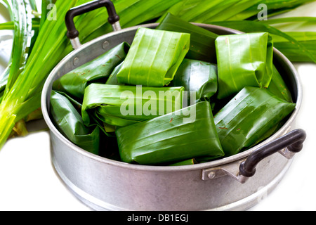 Thai Dessert, Glutinous Reis und Bananen im Bananenblatt wickeln vor gedämpft wird. Stockfoto