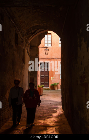 Zwei Menschen, die zu Fuß durch gewölbte Straße in Siena, Italien Stockfoto