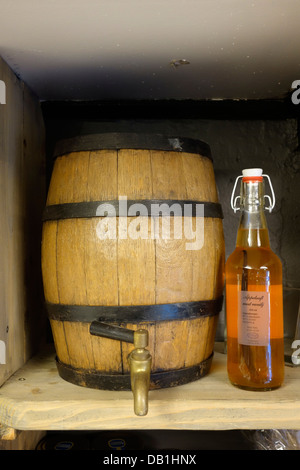 Ein kleines Oakwood Fass platziert auf dem Regal mit einer Flasche von der Seite. Stockfoto