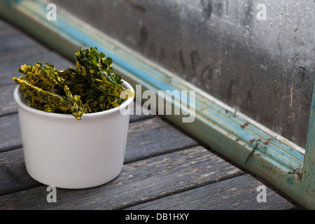 Schüssel mit Grünkohl Chips neben frischen Grünkohl Stockfoto