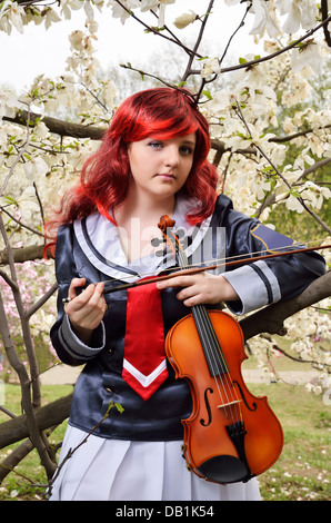 Teenager-Mädchen mit der Geige im blühenden Garten Stockfoto