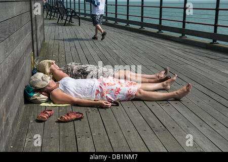 Southend, UK. 22. Juli 2013. Als das Quecksilber Hits 32C zwei Damen aus der Meeresbrise legen und genießen Sie die Sonne am Ende des Southend Pier. Bei 1,33 Meilen (2158m) ist es der längste Vergnügen Pier in der Welt. Bildnachweis: Allsorts Stock Foto/Alamy Live-Nachrichten Stockfoto