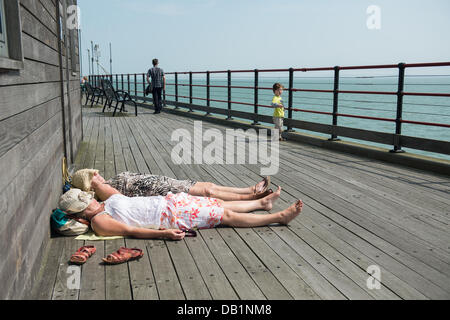 Southend, UK. 22. Juli 2013. Als das Quecksilber Hits 32C zwei Damen aus der Meeresbrise legen und genießen Sie die Sonne am Ende des Southend Pier. Bei 1,33 Meilen (2158m) ist es der längste Vergnügen Pier in der Welt. Bildnachweis: Allsorts Stock Foto/Alamy Live-Nachrichten Stockfoto