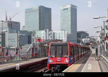 Ein London Docklands Light Railway Zug kommt an Pappel-Station mit dem Geschäftsviertel Canary Wharf im Hintergrund. Stockfoto
