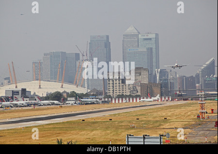 British Airways-Passagier-Jet landet auf dem Flughafen London City. Canary Wharf und den Millennium Dome im Hintergrund Stockfoto