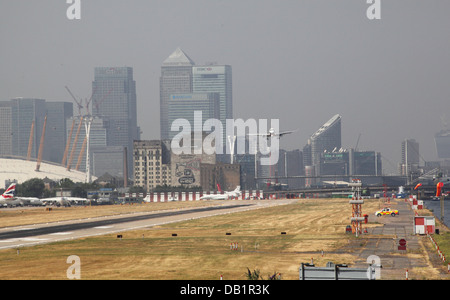 British Airways-Passagier-Jet landet auf dem Flughafen London City. Canary Wharf und den Millennium Dome im Hintergrund Stockfoto