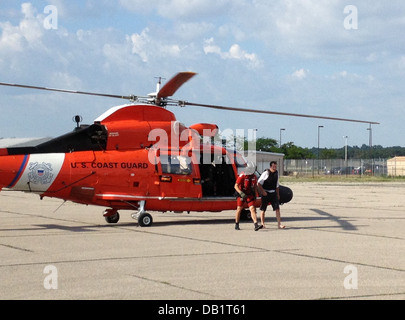 Petty Officer 2. Klasse Erik Lieb, ein Küstenwache Rettungsschwimmer zugewiesen, Air Station Traverse City Escort ein Kajakfahrer, die von der MH-65 Dolphin Helikopter Crew vom East Arm von Grand Traverse Bay, 19. Juli 2013 gerettet wurde. Das Flugpersonal entdeckt die Stockfoto