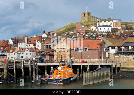 Der Hafen mit dem Rettungsboot vertäut am Kai und Str. Marys Kirche auf den Klippen über, Whitby, Yorkshire, Großbritannien Stockfoto