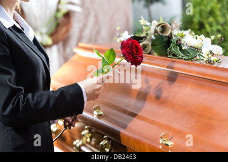 Trauer um Frau auf der Beerdigung mit roter rose Stand am Sarg oder Sarg Stockfoto