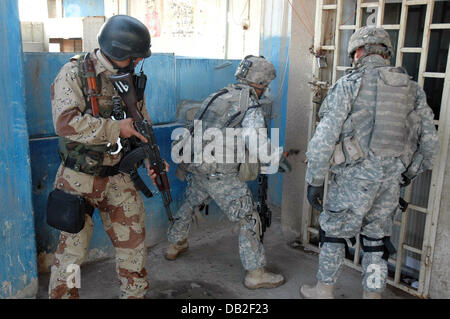Eine amerikanisch-irakischen gemeinsame Patrouille öffnet eine verschlossene Tür, während eine Suche nach versteckten Waffen an der Rennstrecke in Bagdad, Irak, März 2007. Die US-Soldaten gehören zu den 'Apache' 6. Division. Firma 1. Bataillon 23. Infanterie, die irakische Soldaten (L) gehört zu der 6. Division. Foto: Carl Schulze Stockfoto