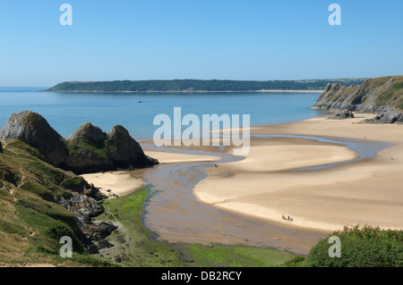 Ein flacher Stream läuft über Goldstrand zwischen den Klippen von Herbst Bay und drei Klippen. Oxwich Punkt Hintergrund Stockfoto
