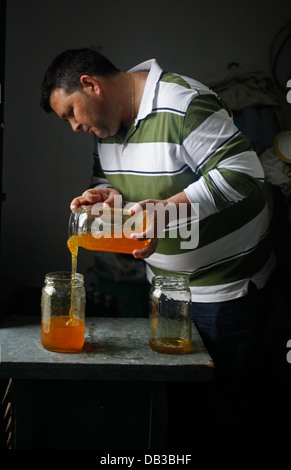 Ein Arbeiter füllt ein Honigtopf mit Honig aus einem anderen Topf in Puremiel, ein Honig-Unternehmen, das produziert Bio rohen-Honig, Cadiz, Spanien Stockfoto