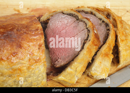 Ein Rindfleisch Wellington oder Boeuf de Rolle, in Scheiben geschnitten auf ein Schneidbrett aus Holz mit einem Schnitzmesser Stockfoto