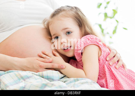 Kind Mädchen hören Bauch der schwangeren Mutter Stockfoto