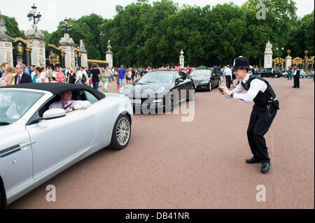 London, UK. 23. Juli 2013. Die Unternehmerpreise am Buckingham Palace, London statt. Wie die Autos draußen Schlange stehen, um die Sicherheit überprüft werden, wird ein Gast ein Polizist, ein Kinderspiel von ihm im Buckingham Palace zu bekommen. Bildnachweis: Allsorts Stock Foto/Alamy Live-Nachrichten Stockfoto