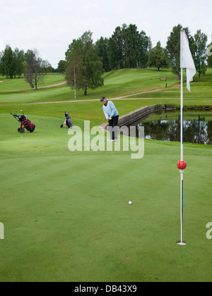 Senioren Golf spielen, gekleidet in schwarz und blau, auf dem fairway Stockfoto