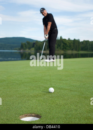 Senioren Golf spielen, in schwarz gekleidet. Aktion erschossen auf dem Grün Stockfoto