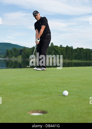 Senioren Golf spielen, in schwarz gekleidet. Aktion erschossen auf dem Grün Stockfoto