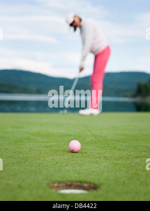 Senioren Golf spielen, in rosa gekleidet. Aktion erschossen auf dem Grün Stockfoto