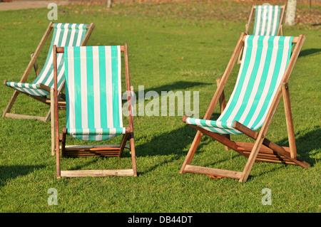 Vier grüne gestreifte Liegestühle am grünen Rasen. Stockfoto