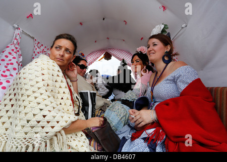 Frauen tragen spanische Flamenco-Kleider in Gypsy Horse-drawn Wagen auf dem Pilgerweg nach El Rocio in Spanien Stockfoto