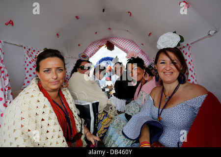 Frauen tragen spanische Flamenco-Kleider in Gypsy Horse-drawn Wagen auf dem Pilgerweg nach El Rocio in Spanien Stockfoto