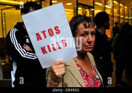 Ein weiblicher Demonstrant hält ein Plakat lesen "ATOS tötet" London, Vereinigtes Königreich Stockfoto