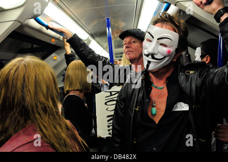 Ein Mann mit einem anonymen Maske fährt mit der u-Bahn, London, UK Stockfoto